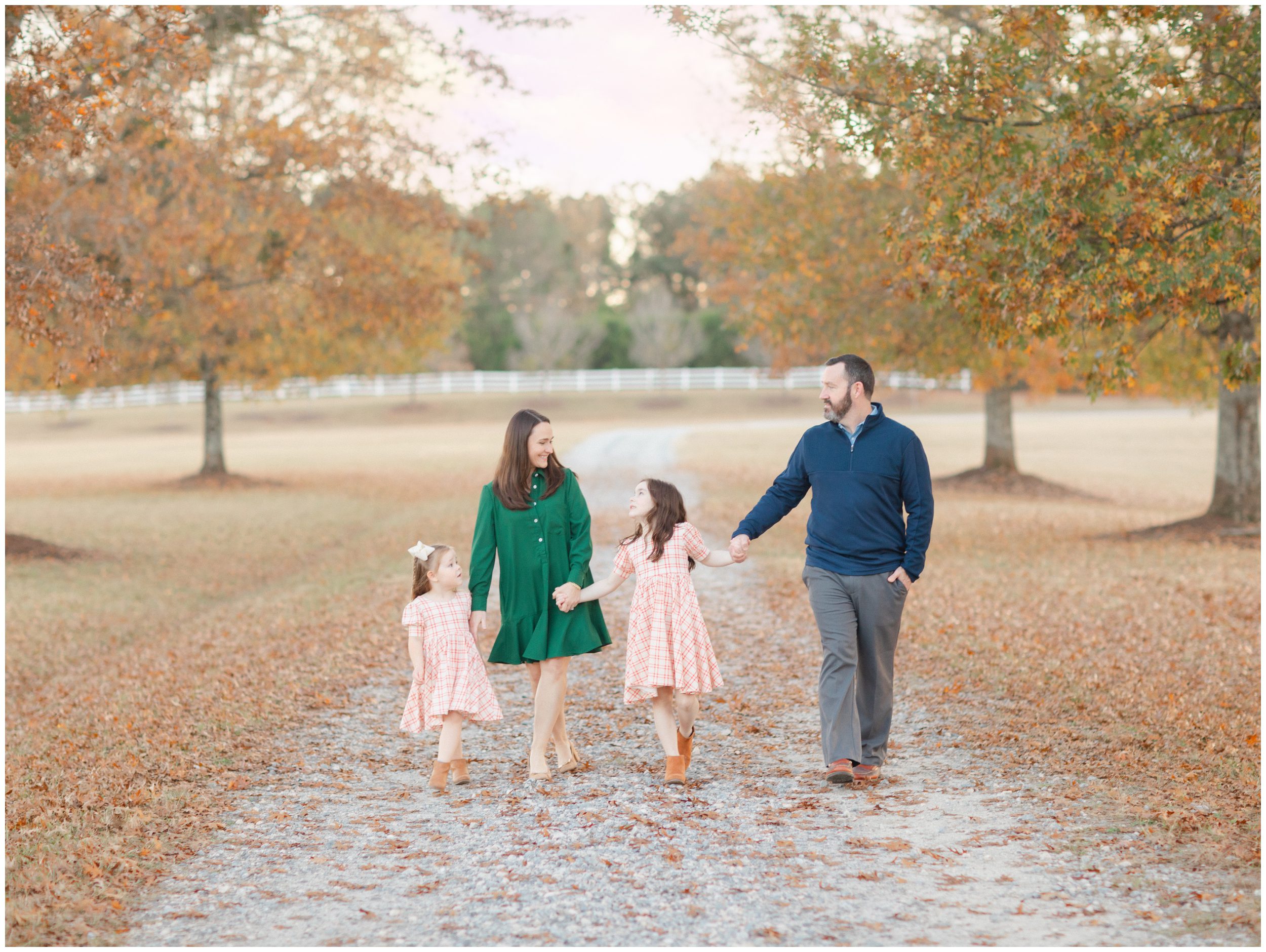 Family of four walking together beneath autumn trees during a fall portrait session in Oconee County GA