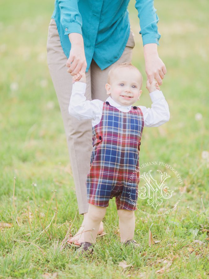 photo of baby boy walking with help from mom.