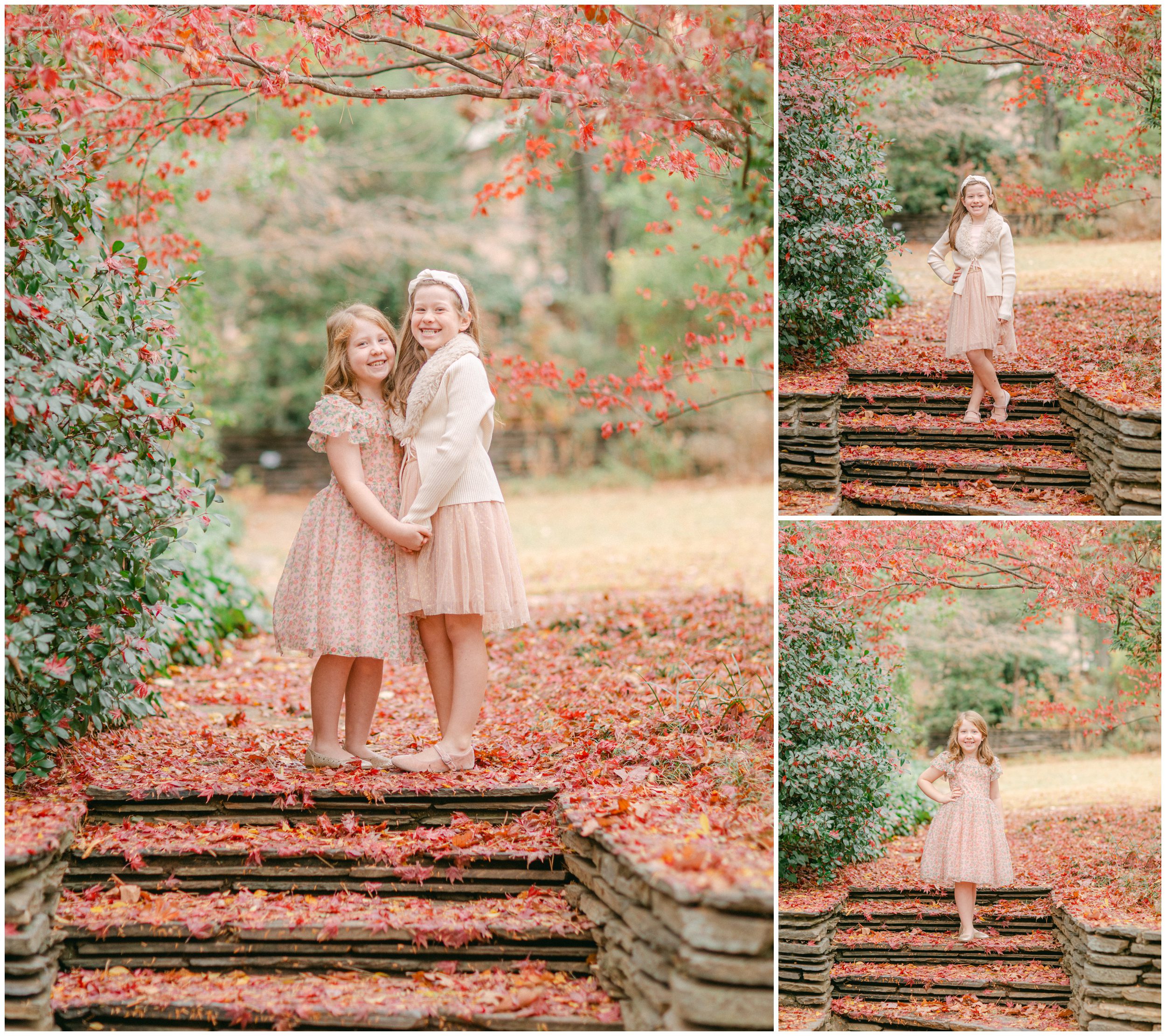 Two sisters posing on leaf-covered stone steps beneath vibrant red Japanese maple trees at UGA Founder's Garden in Athens, Georgia.