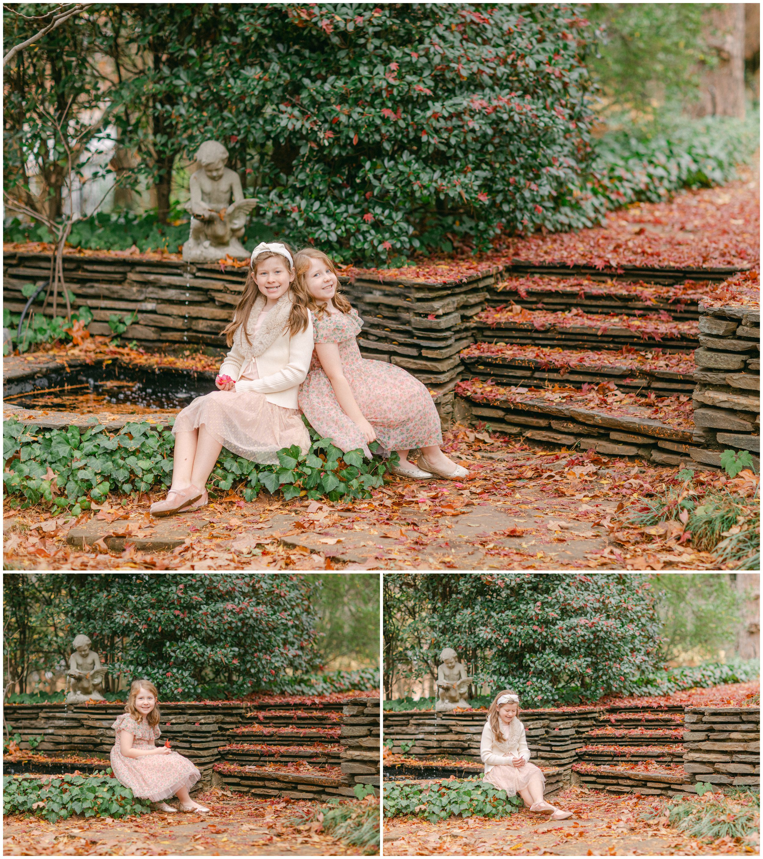 Two young sisters enjoying fall portraits beside a stone fountain and autumn leaves at Founder's Garden on UGA's campus.