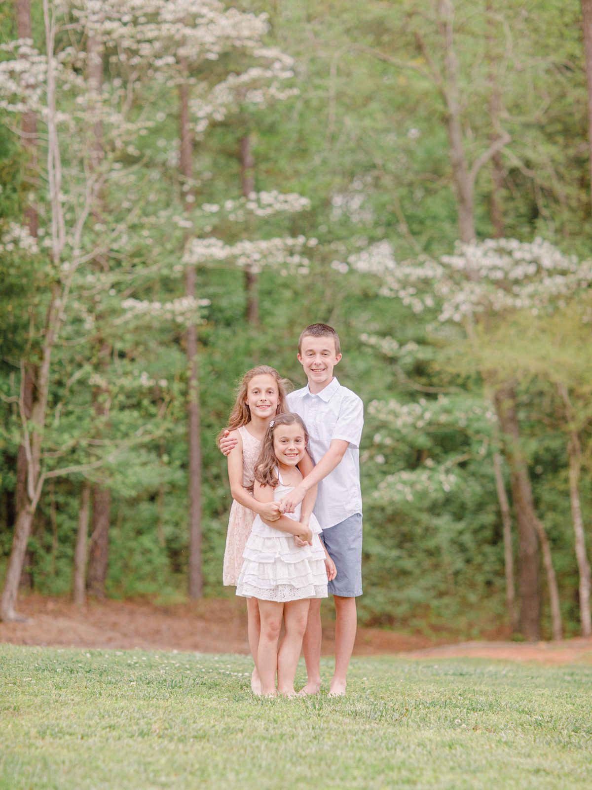 Portrait of three siblings during their dogwood blossom Spring kids photography session in Oconee County, GA.