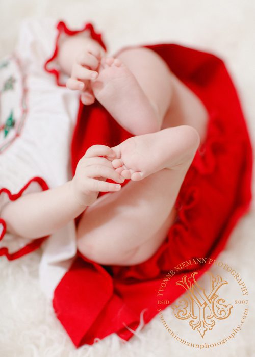 Photo of four month old holding her toes in Christmas outfit in Bishop, GA.