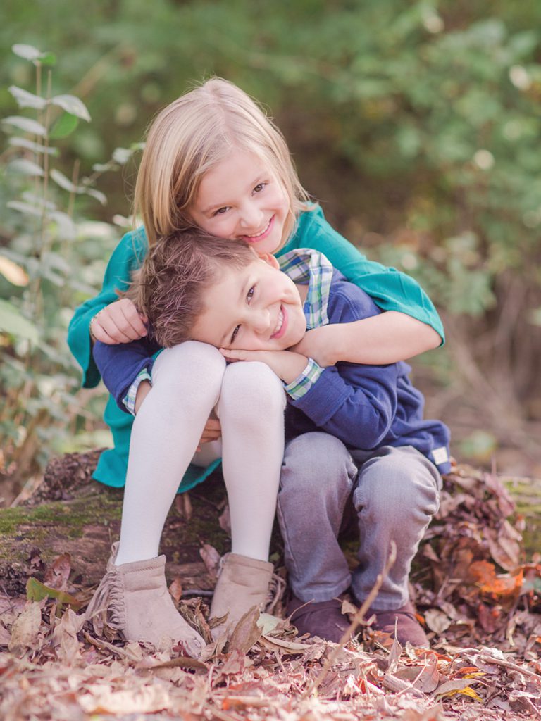 Sibling photo of brother and sister hugging playfully in the woods taken by Athens GA lifestyle photographer.