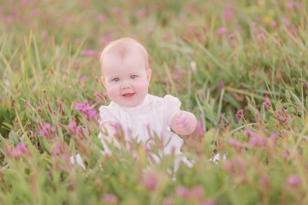 Athens, GA baby photographer creates beautiful portrait of a seven month old girl in a field of purple flowers wearing her baptism dress.