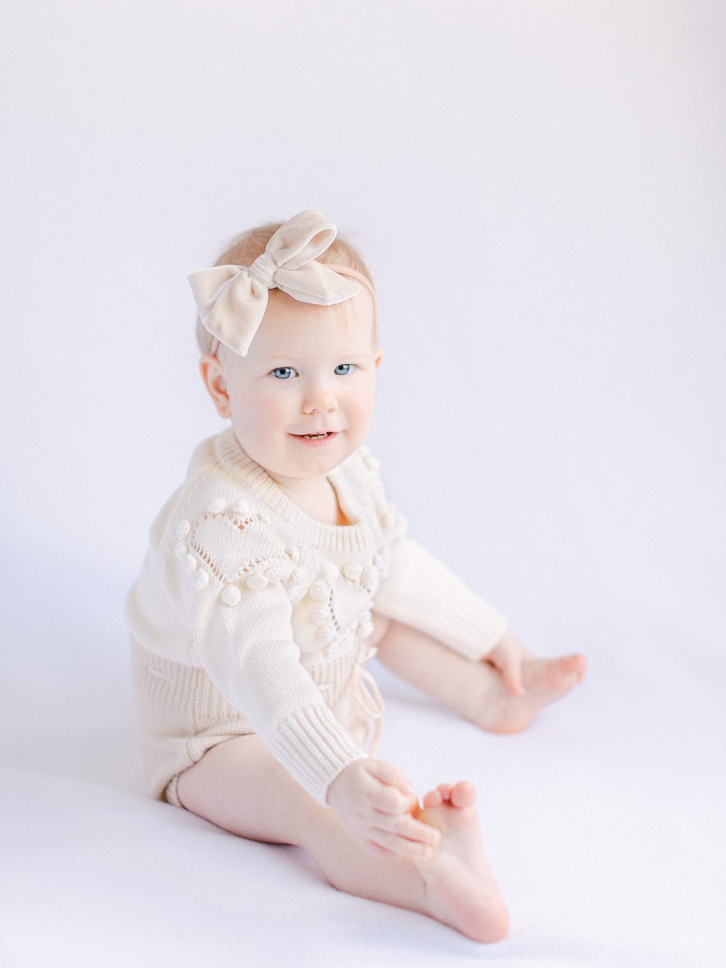 Photo of baby girl on white backdrop for her first birthday baby photography shoot in Knoxville, TN.