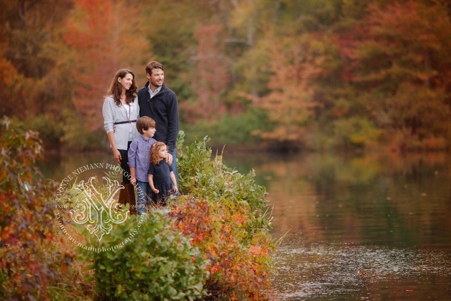 Fall family portraits taken in Athens, GA at a local lake surrounded by vibrant trees.