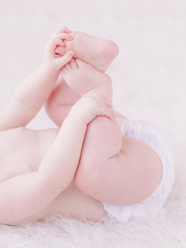 Nine months milestones of baby holding toes.