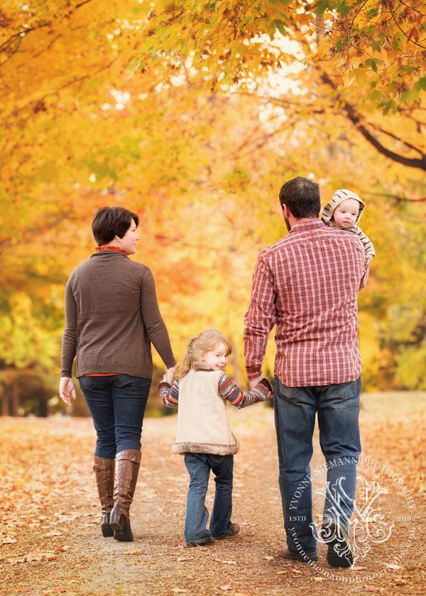 Casual family photo surrounded by beautiful yellow fall leaves taken by Yvonne Niemann Photography.