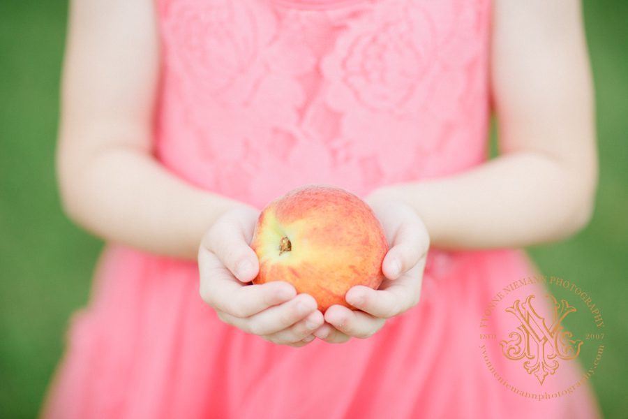 Picture of a girl holding a peach as an announcement of Yvonne Niemann Photography moving to Athens, GA.