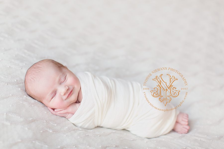 Newborn photography of a 9 day old baby smiling while sleeping taken by Yvonne Niemann Photography.