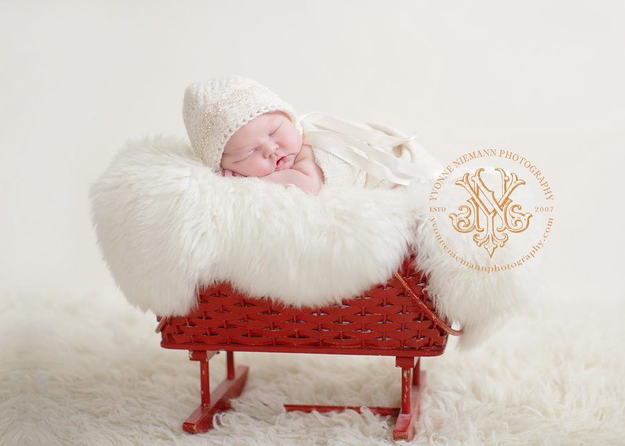 Pretty newborn photography of a baby girl in a red craddle taken in Millstadt, IL by Yvonne Niemann Photography.