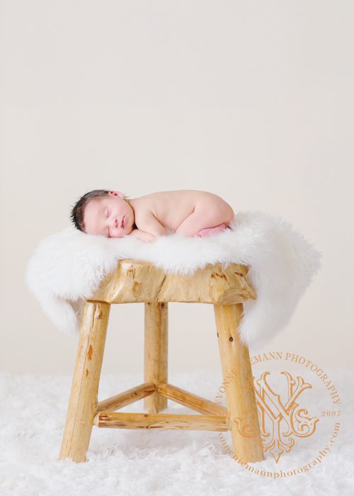 Sweet newborn portrait on natural wooden stool taken by Yvonne Niemann photography in St. Louis.